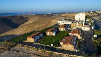 Vista aèria d'una zona residencial amb cases, un edifici gran i blanc, i una carretera.