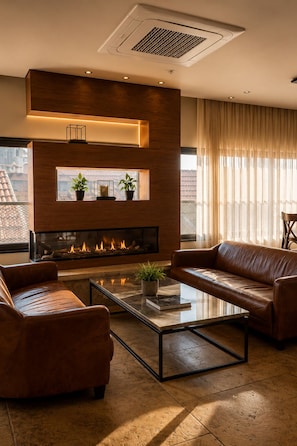 Una sala de estar moderna con chimenea, sofás de cuero y una mesa de centro de vidrio.