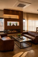 Una sala de estar moderna con chimenea, sofás de cuero y una mesa de centro de vidrio.