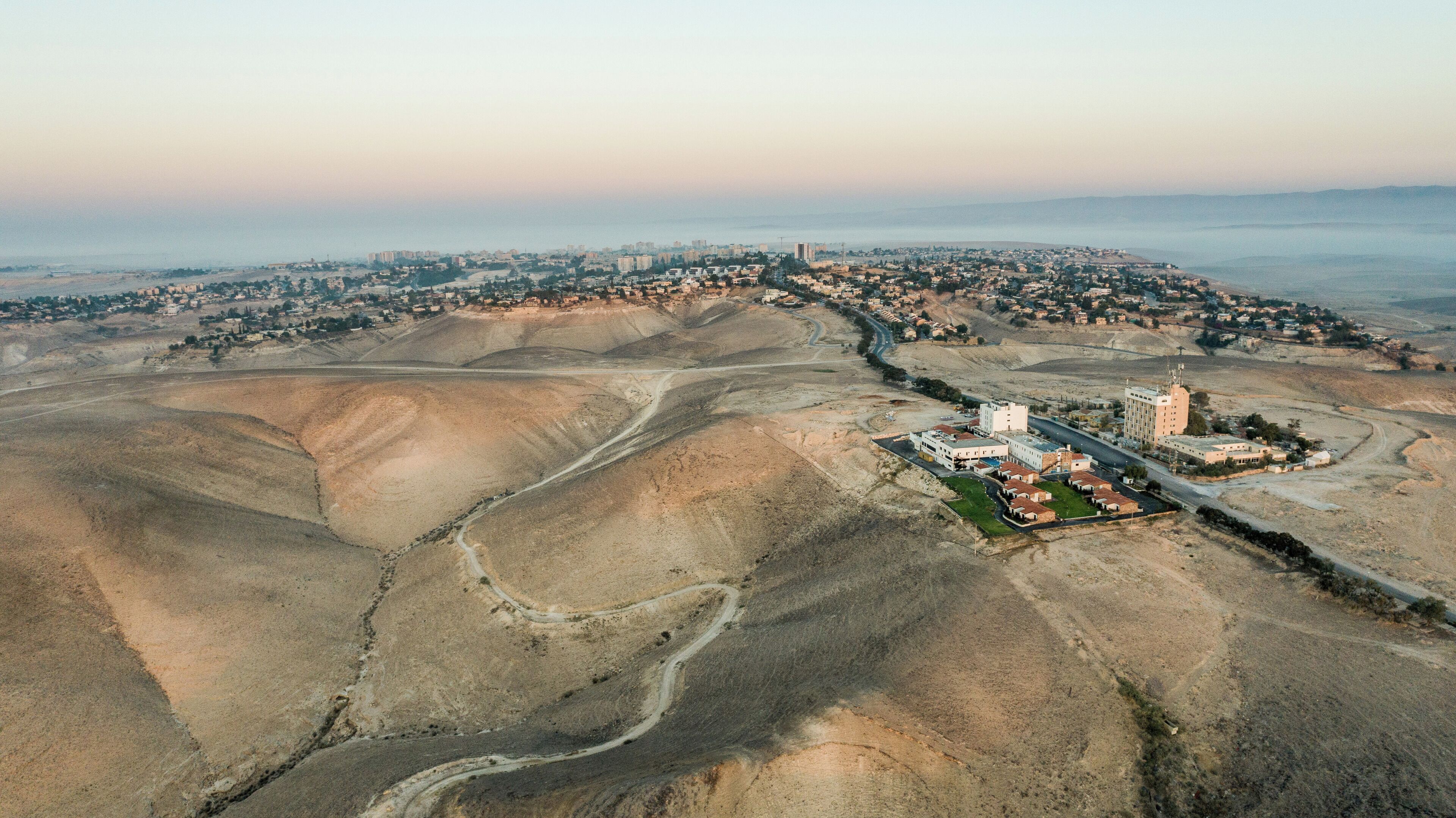 Vista aérea de un paisaje desértico con un pueblo pequeño y un complejo de edificios grande.