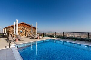 Una piscina en la azotea con sillas de descanso y un edificio de piedra al fondo.