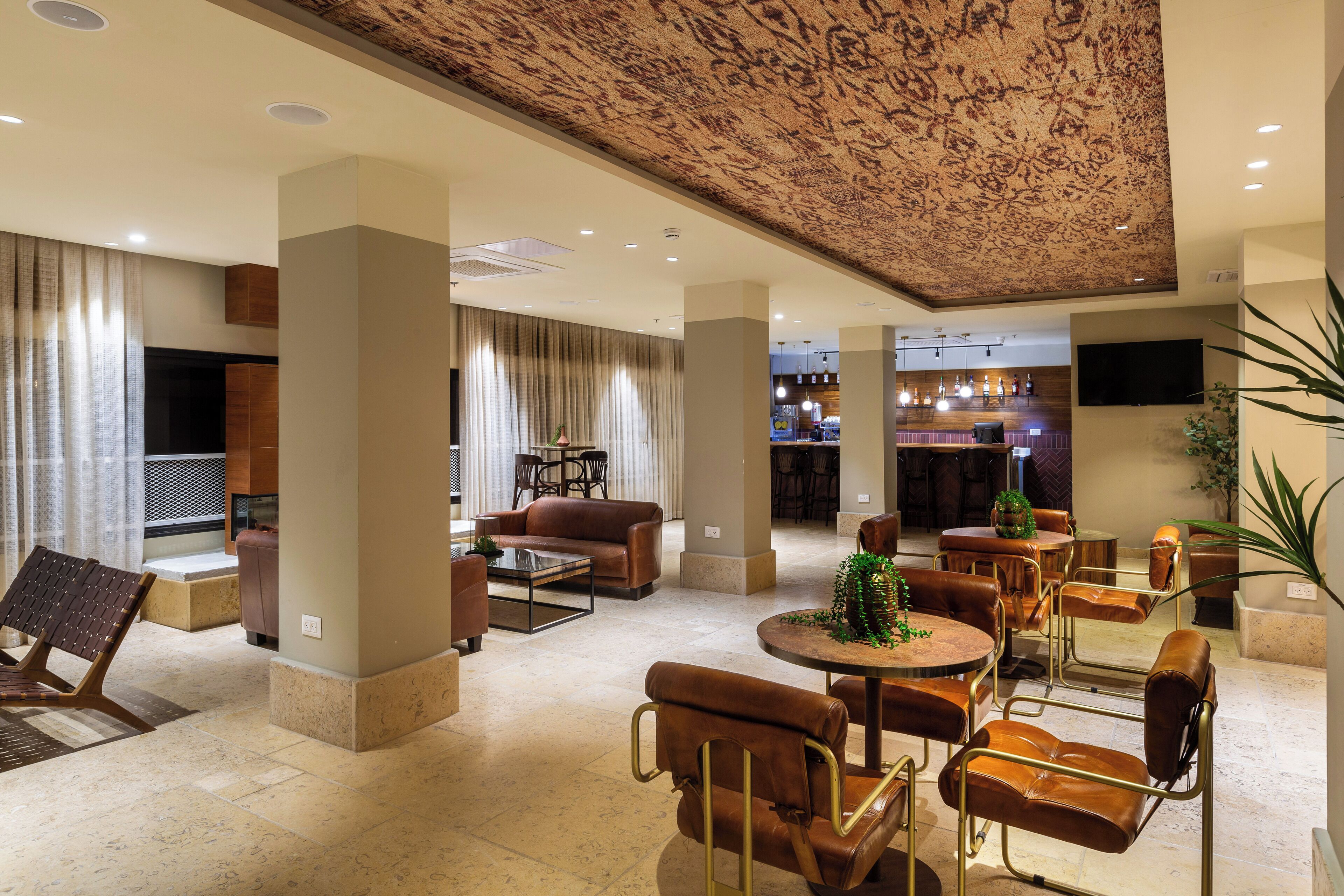 Un hall d’entrée spacieux avec un plafond haut, des coins salon confortables et un bar à l’arrière-plan.