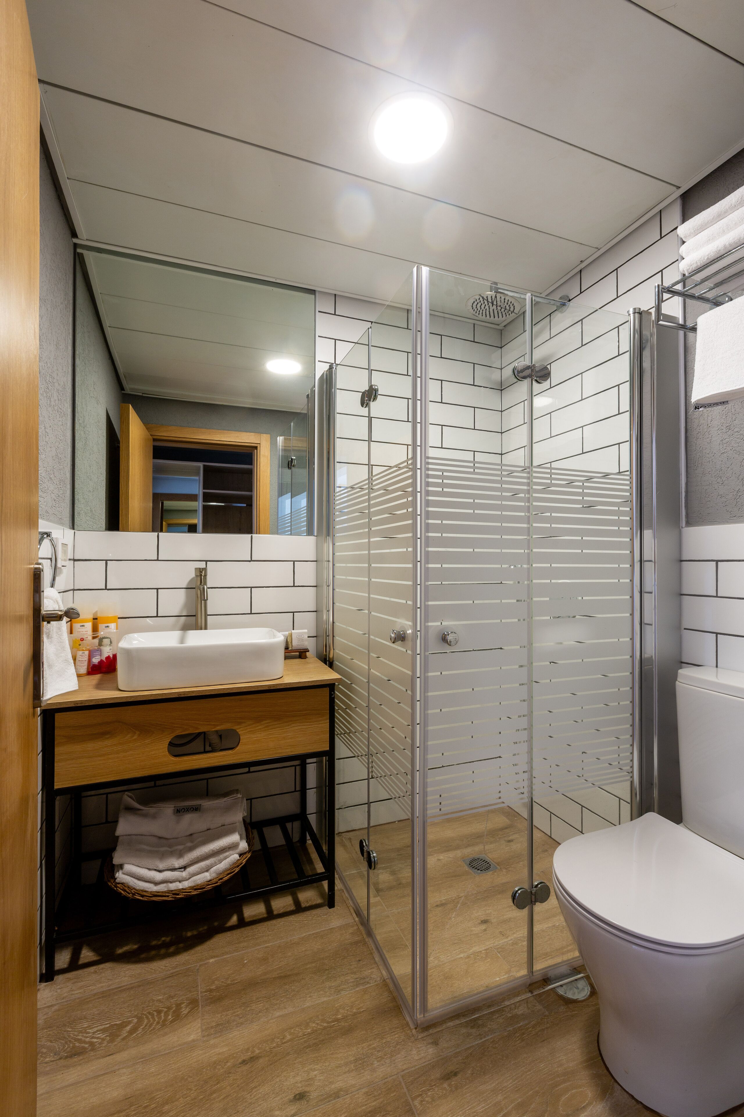 A modern bathroom with a glass-enclosed shower, a white sink, and a toilet.