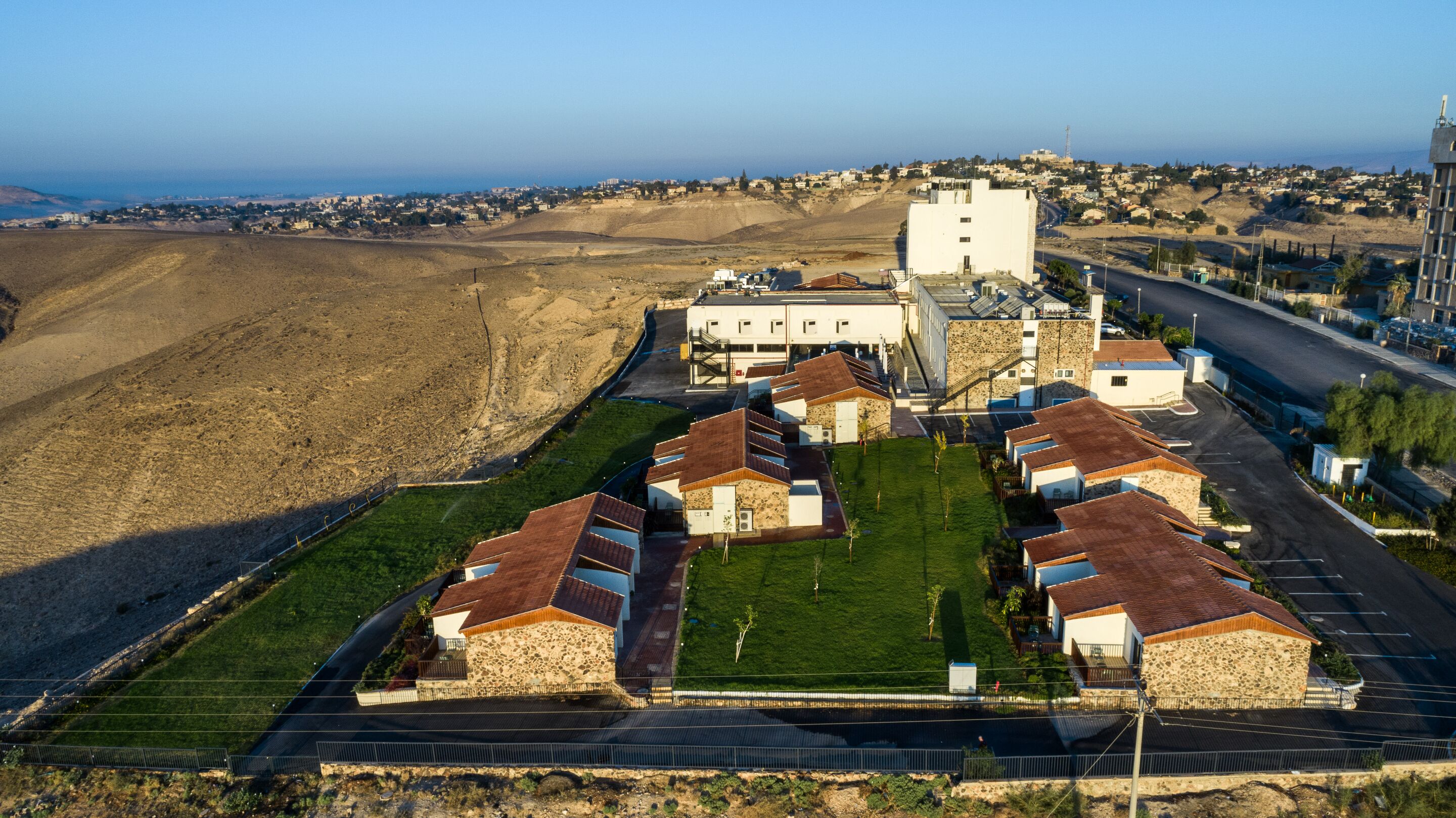 A residential area with stone houses, a central white building, and a view of the sea.