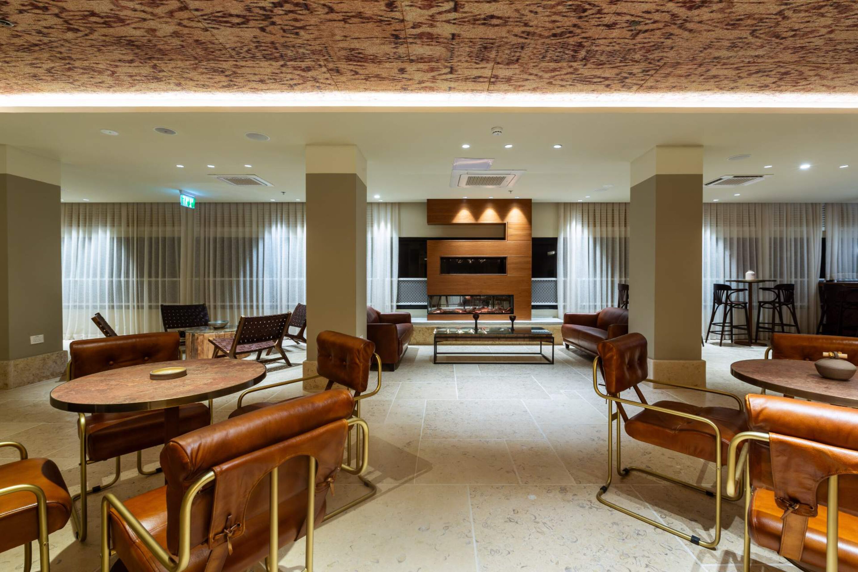 A spacious lounge area with leather seating, a central fireplace, and a modern design.