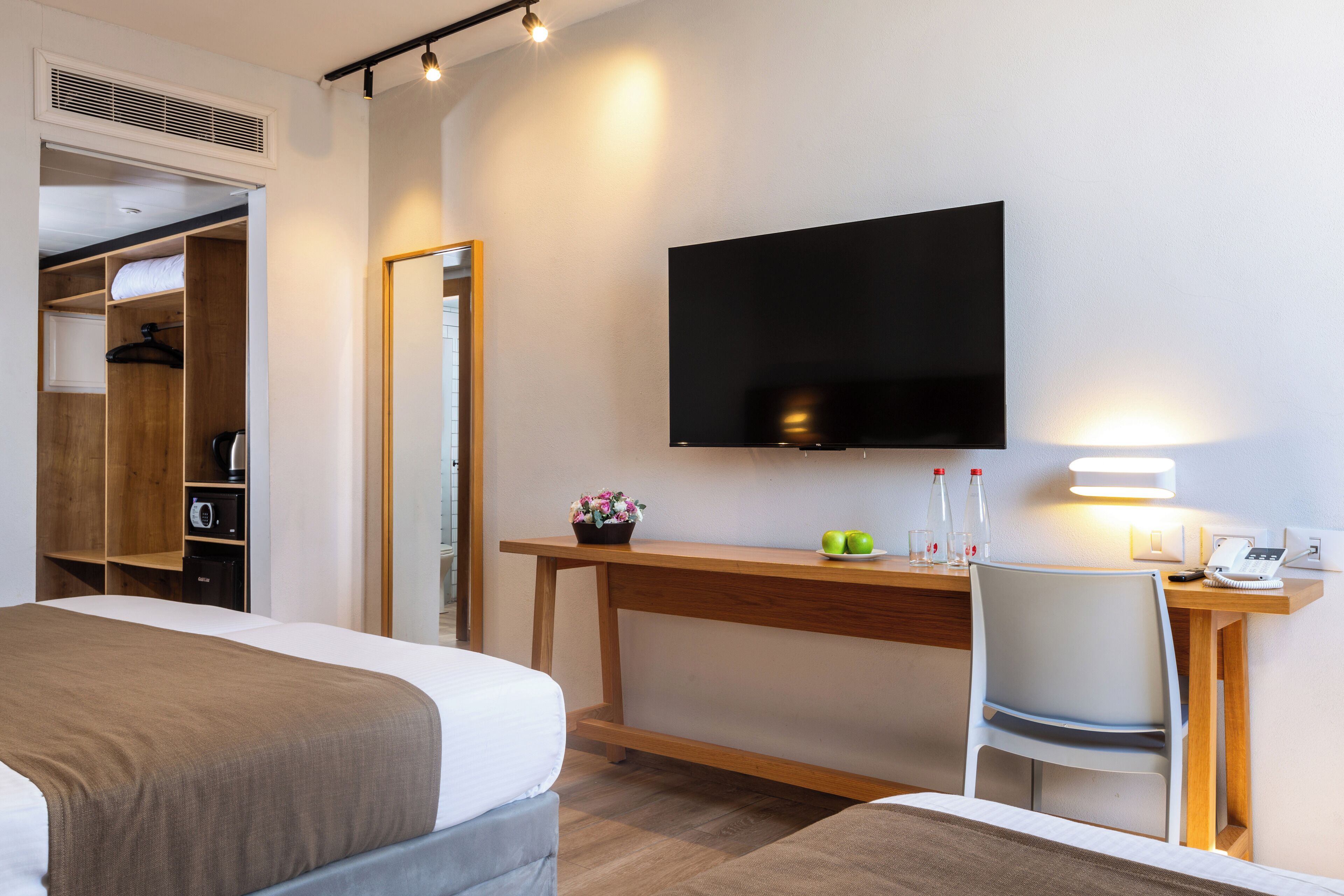 A hotel room with a bed, a desk with a chair, a TV, and a wardrobe.