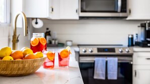 A kitchen with a wooden bowl of oranges, a jar of orange slices, and two glasses of orange juice. - Casita with Cowboy Tub & Four Peaks Wilderness (Scottsdale)