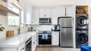 A modern kitchen with white cabinets, stainless steel appliances, and a blue chair. - Casita with Cowboy Tub & Four Peaks Wilderness (Scottsdale)