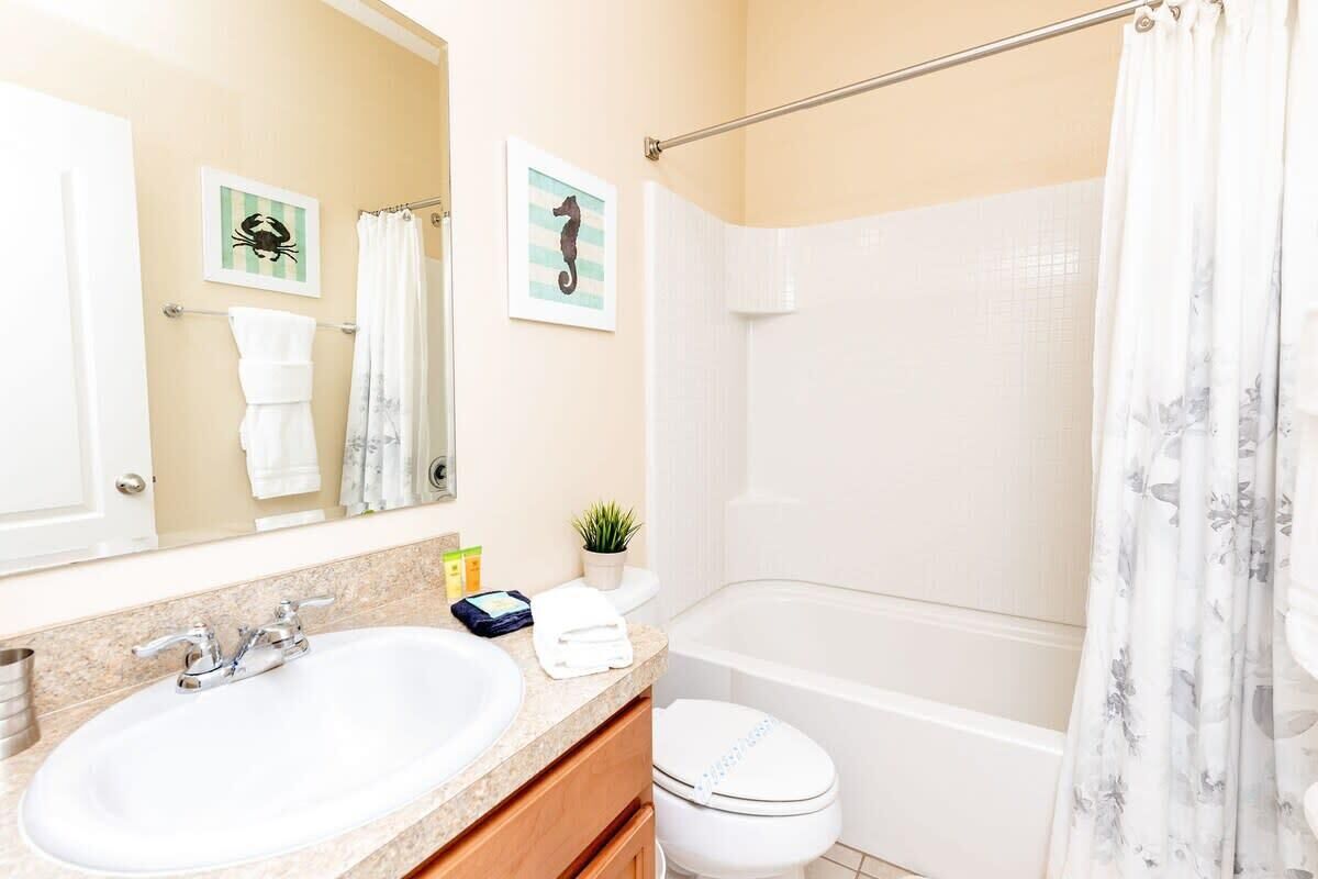 A bathroom with a sink, mirror, toilet, and bathtub.