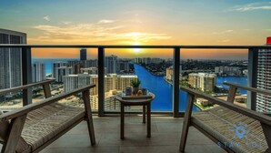 Un balcon avec vue sur la ville et une rivière. On y trouve deux fauteuils confortables et une petite table avec un plateau.