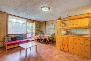 A cozy room with a wooden bench, a dining table with chairs, and a kitchen area with wooden cabinets. - Appartamento Bareu Mountain View (Sauze d'Oulx)