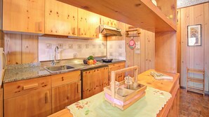 Una cocina de madera con encimera de granito, pileta de acero inoxidable y alacenas de madera.