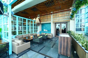 A spacious indoor area with a high ceiling, wooden beams, and a seating area with sofas and tables.