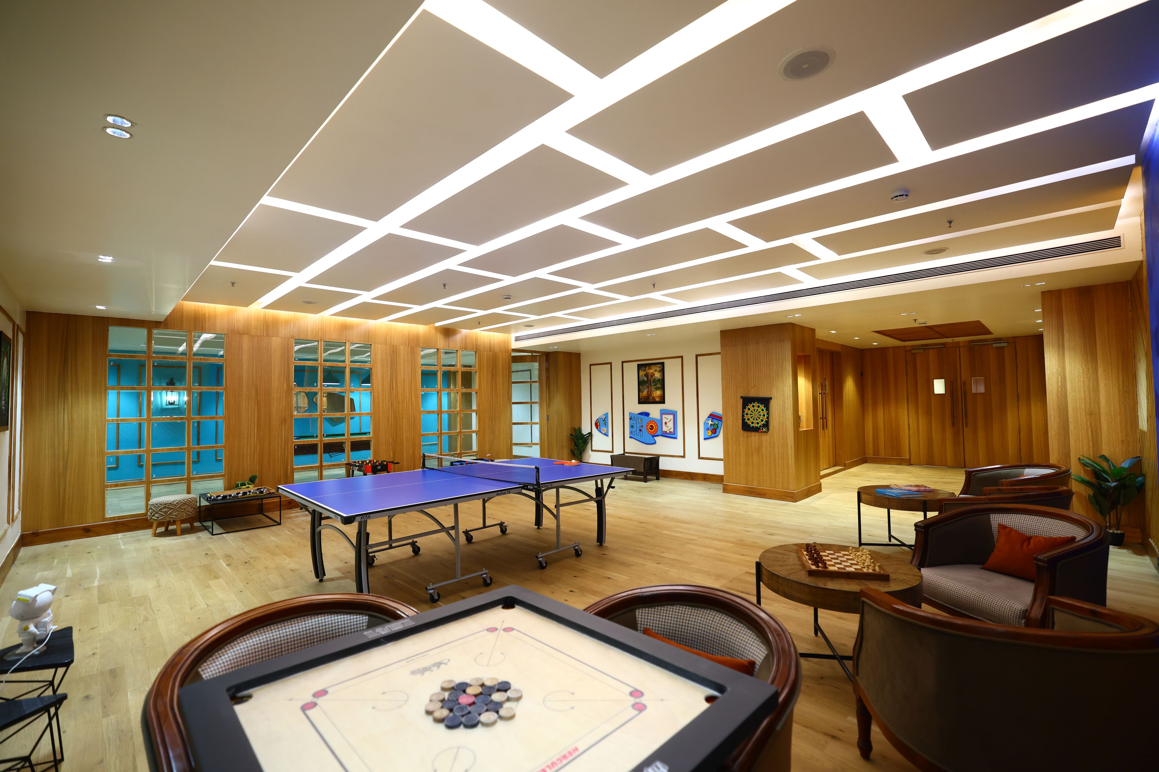 A room with a ping pong table, foosball table, and a dartboard.