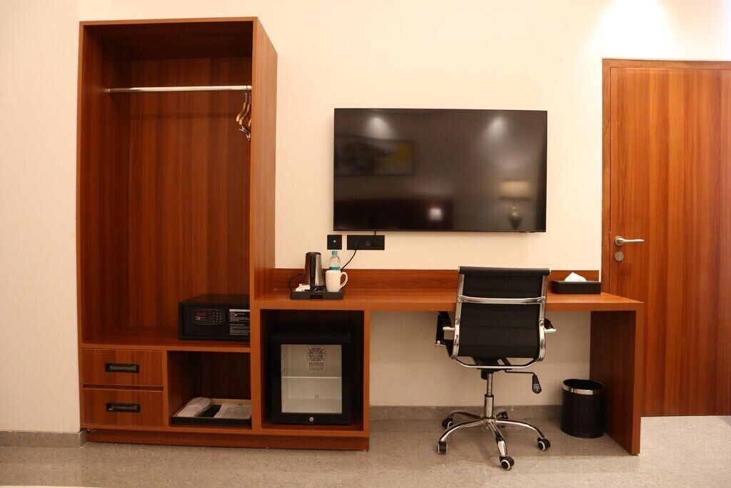 A compact office space with a wooden desk, a black office chair, a flat-screen TV, and a filing cabinet.