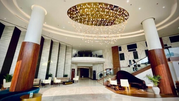 A spacious lobby with a grand chandelier, high ceilings, and a central staircase. - Mars Resorts (Meerut)