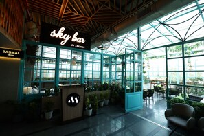 A sky bar with a modern design, featuring a glass enclosure, potted plants, and a sign indicating the bar's name. - Mars Resorts (Meerut)