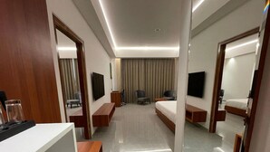 A modern hotel room with a large bed, a desk, a chair, and a TV. - Mars Resorts (Meerut)