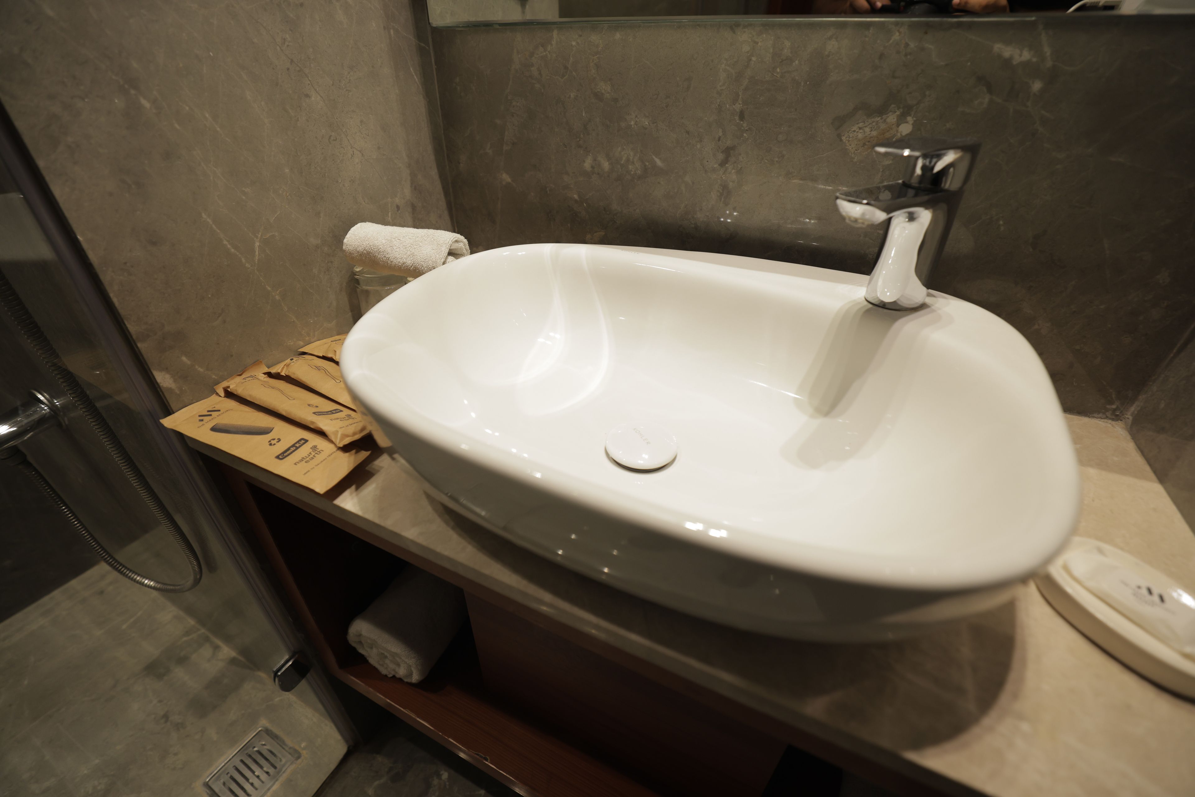 Une salle de bain avec un lavabo blanc, une serviette et une boîte sur le comptoir.
