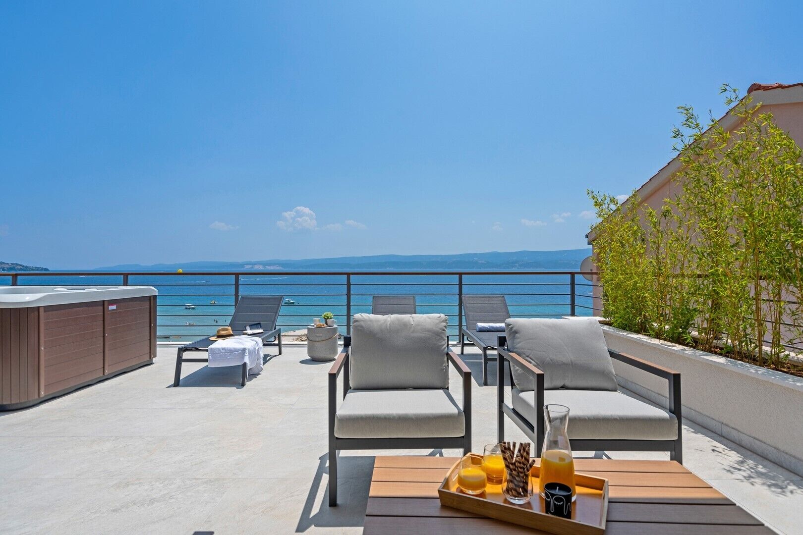 A rooftop terrace with lounge chairs, a hot tub, and a tray with drinks and snacks.