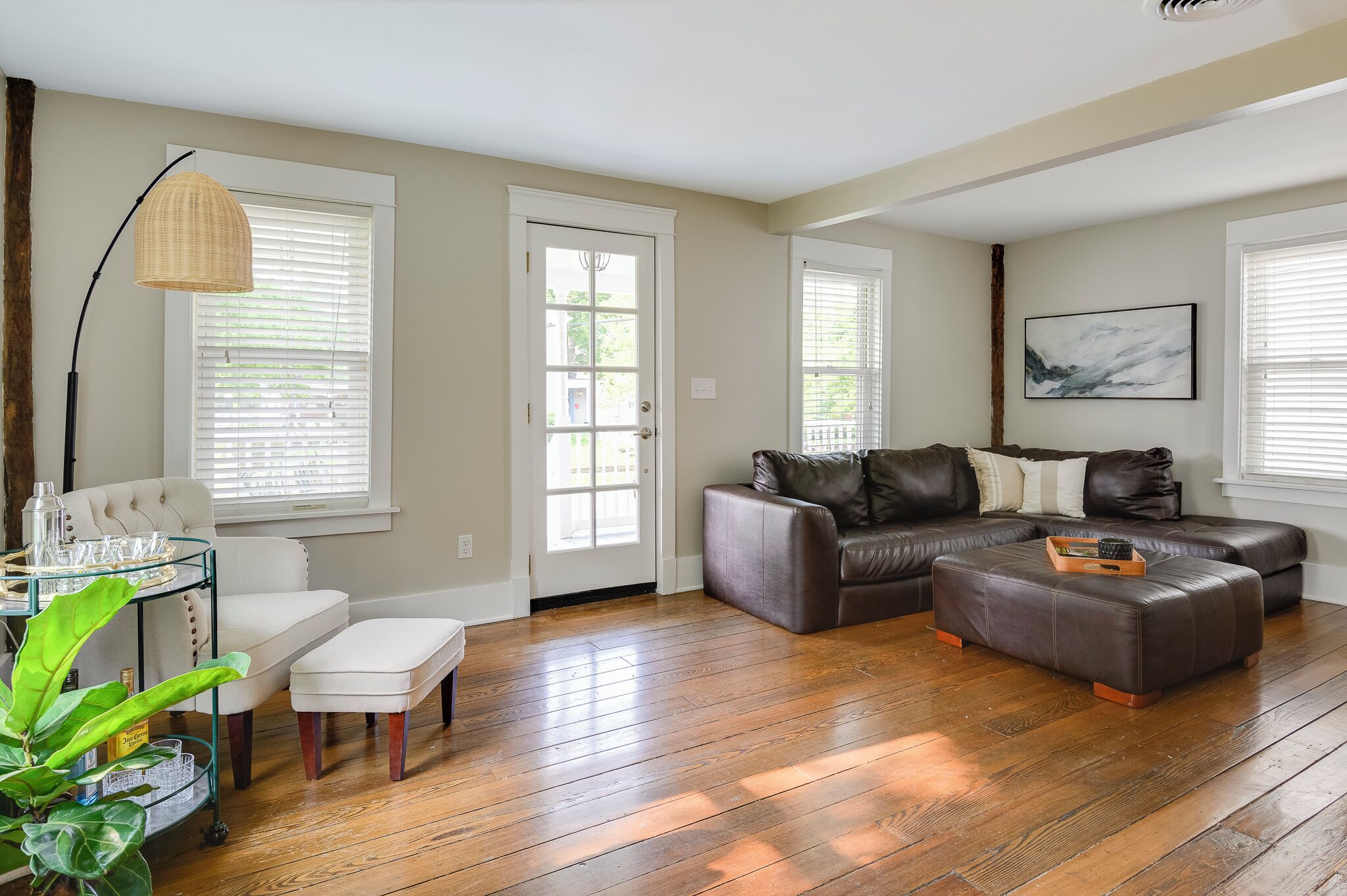 A living room with a sectional sofa, a white armchair, a glass coffee table, and a floor lamp.