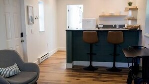 Quarto com cozinha compacta, um banco de bar, uma cadeira e uma mesa de jantar.