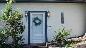 Uma casa com porta branca, placa de identificação e coroa de flores na porta.