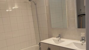 A bathroom with a bathtub, a shower, a sink, and a mirror. - Spacieux Appartement sur la Murette (La Murette)