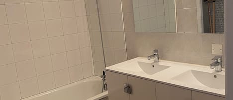 A bathroom with a bathtub, a shower, a sink, and a mirror.