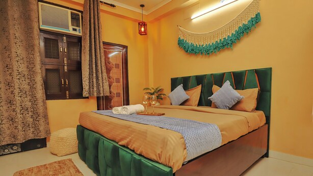 Una camera da letto con un letto imbottito verde, una testiera in legno, un comodino con un bicchiere e un elemento decorativo a parete.