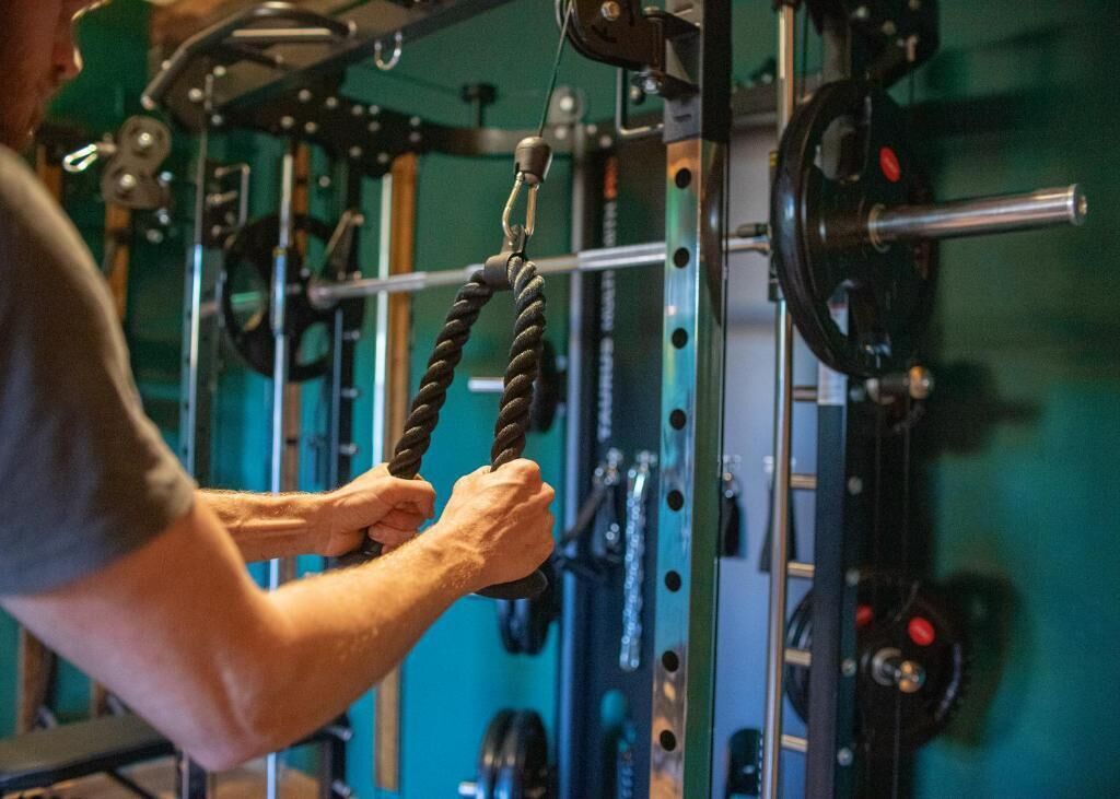 Persona usando una máquina de poleas con un mango de cuerda en un gimnasio.