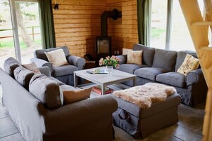Ein gemütliches Wohnzimmer mit Kamin, grauen Sofas und einem Couchtisch mit Blumen in einer Vase.