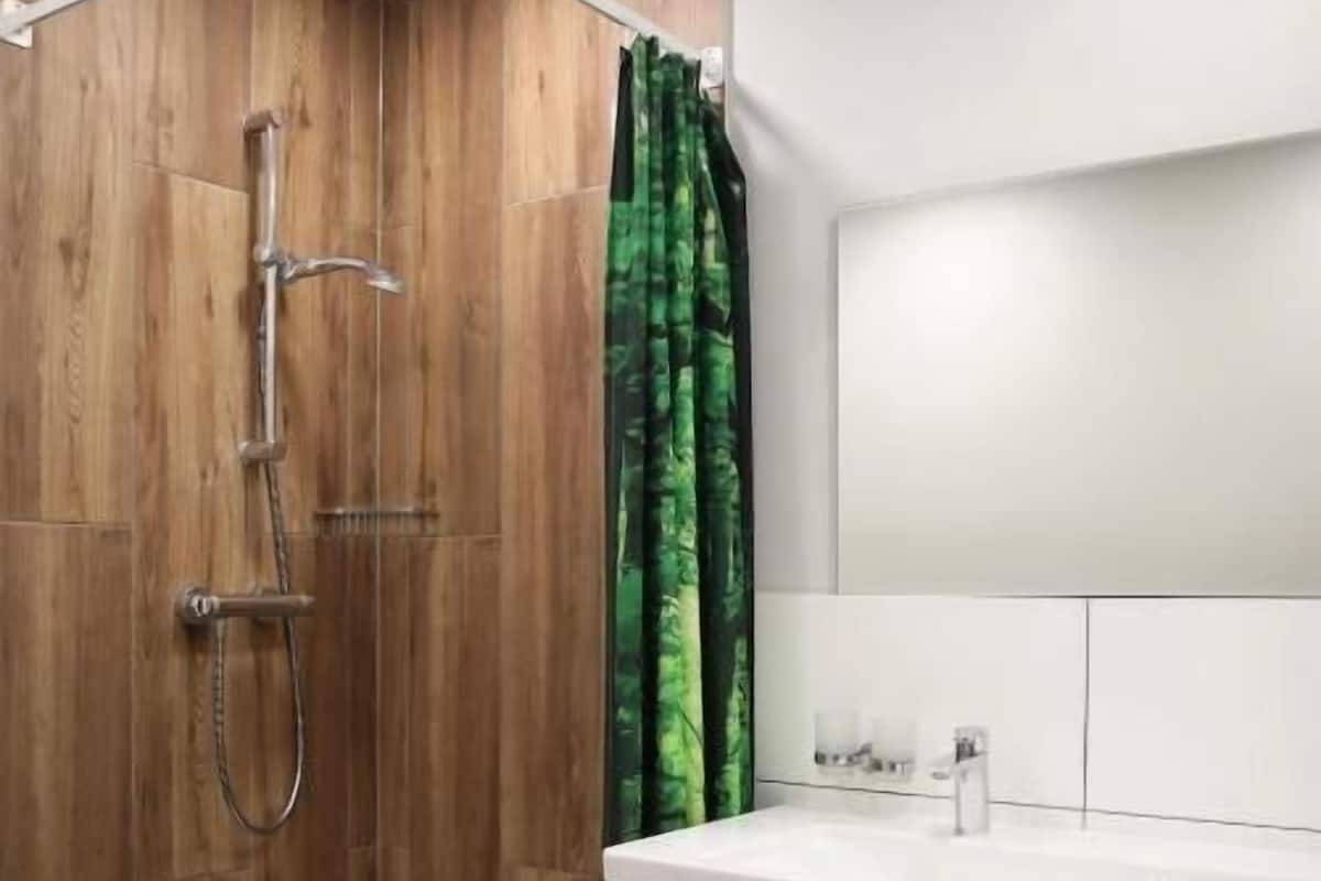 Une salle de bain moderne avec une cabine de douche en bois, un lavabo blanc avec un miroir et un meuble blanc.