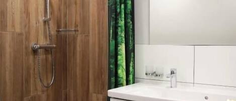 A modern bathroom with a wooden shower enclosure, a white sink with a mirror, and a white cabinet.