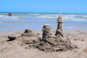 A sandy beach with a large sandcastle and a conical structure.