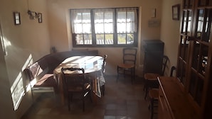 Ein Essbereich mit einem runden Tisch, Stühlen und einem Fenster mit Spitzenvorhängen.