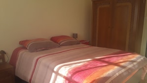 Ein Schlafzimmer mit Bett, Kissen, einem Nachttisch, einem Kleiderschrank und einer Lampe.