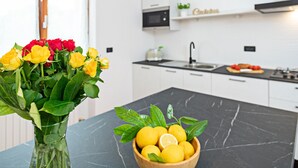 Eine moderne Küche mit weißen Schränken, einer schwarzen Marmorarbeitsplatte, einer Vase mit gelben und roten Rosen sowie einer Zitronenschale.