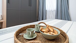 Ein Frühstücksbrett mit zwei Tassen und einer Schüssel mit Cantuccini auf einer gewebten Matte.
