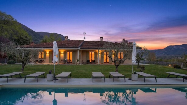 Ein Haus mit Swimmingpool, Liegestühlen und Bergblick.