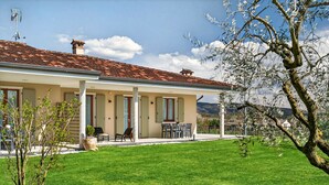 A two-story house with a tiled roof, a covered patio with outdoor furniture, and a well-maintained lawn. - Regarda - "Villa Ida, Giarole unit" with pool and bisg garden (Costermano)