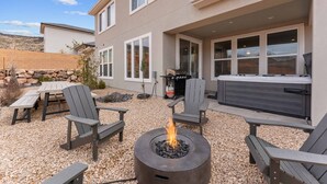A patio area with Adirondack chairs, a fire pit, and a hot tub. - Family Desert Oasis 5 Bedroom Home (Washington)