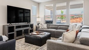A modern living room with a large flat-screen TV, grey sofas, a coffee table, and a TV stand. - Family Desert Oasis 5 Bedroom Home (Washington)