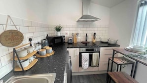 A modern kitchen with a black countertop, white cabinets, and a hanging sign. - Cute+Cozy Guesthouse for 2 +secure offroad parking (Wolverhampton)