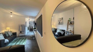 Ein modernes Wohnzimmer mit einer Couch, einem Couchtisch und einem großen Spiegel.