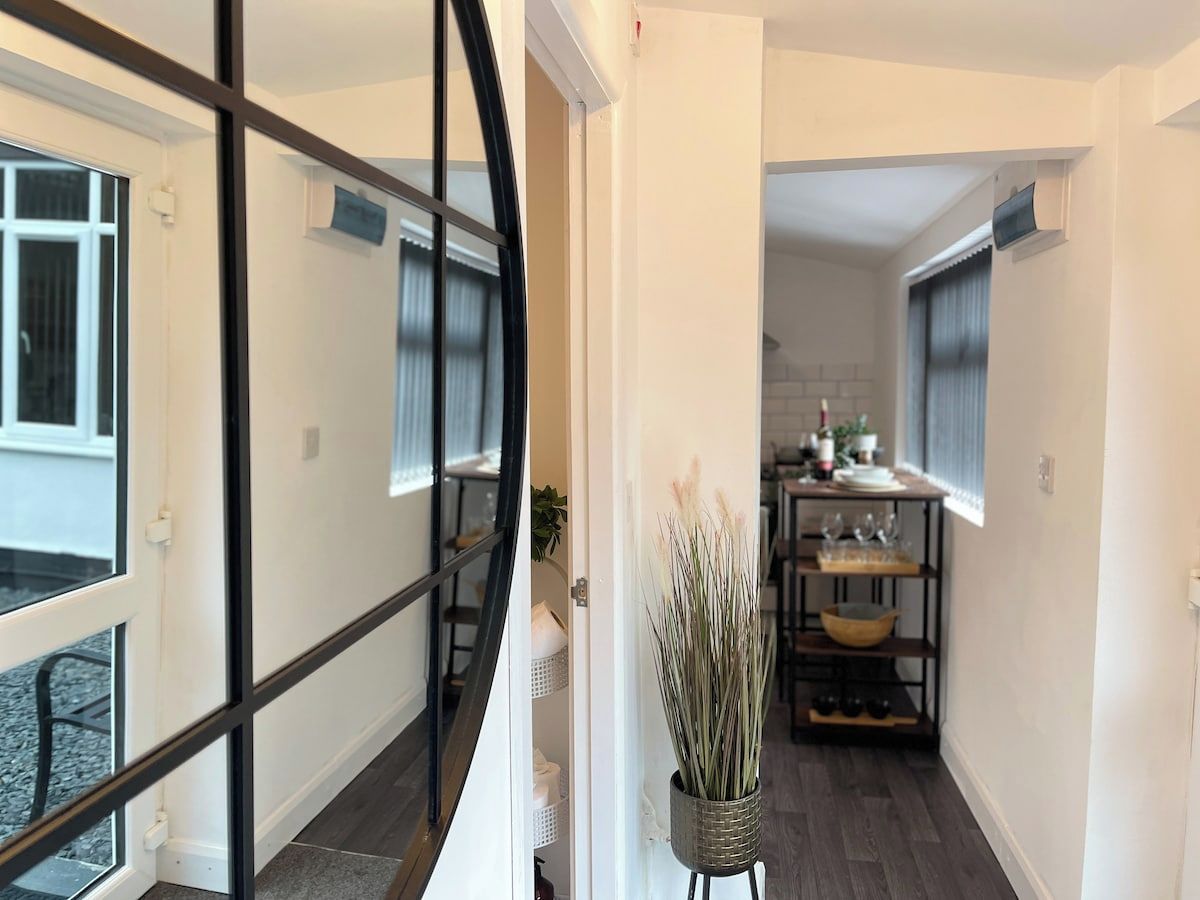 Un interior moderno con una escalera, una zona de comedor con mesa y sillas, y una planta en maceta.