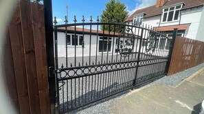 A gated property with a driveway leading to a white building with a red-tiled roof.