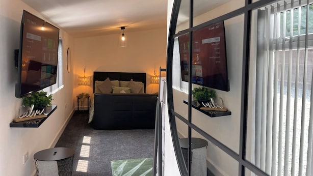 A modern bedroom with a bed, a TV, and a large window. - Cute+Cozy Guesthouse for 2 +secure offroad parking (Wolverhampton)