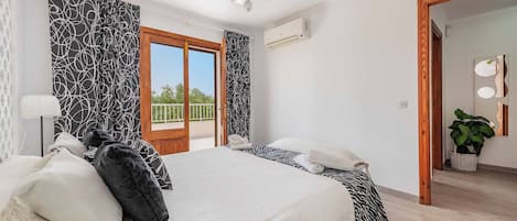 A hotel room with a bed, a balcony, a ceiling fan, and a large mirror.