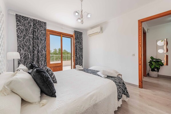 Una habitación de hotel con cama, balcón, ventilador de techo y un espejo grande.